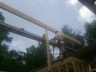Carpenter setting a ridge beam over a new addition frame — Ice Dam Removal by Roofing Brothers in Bradley
