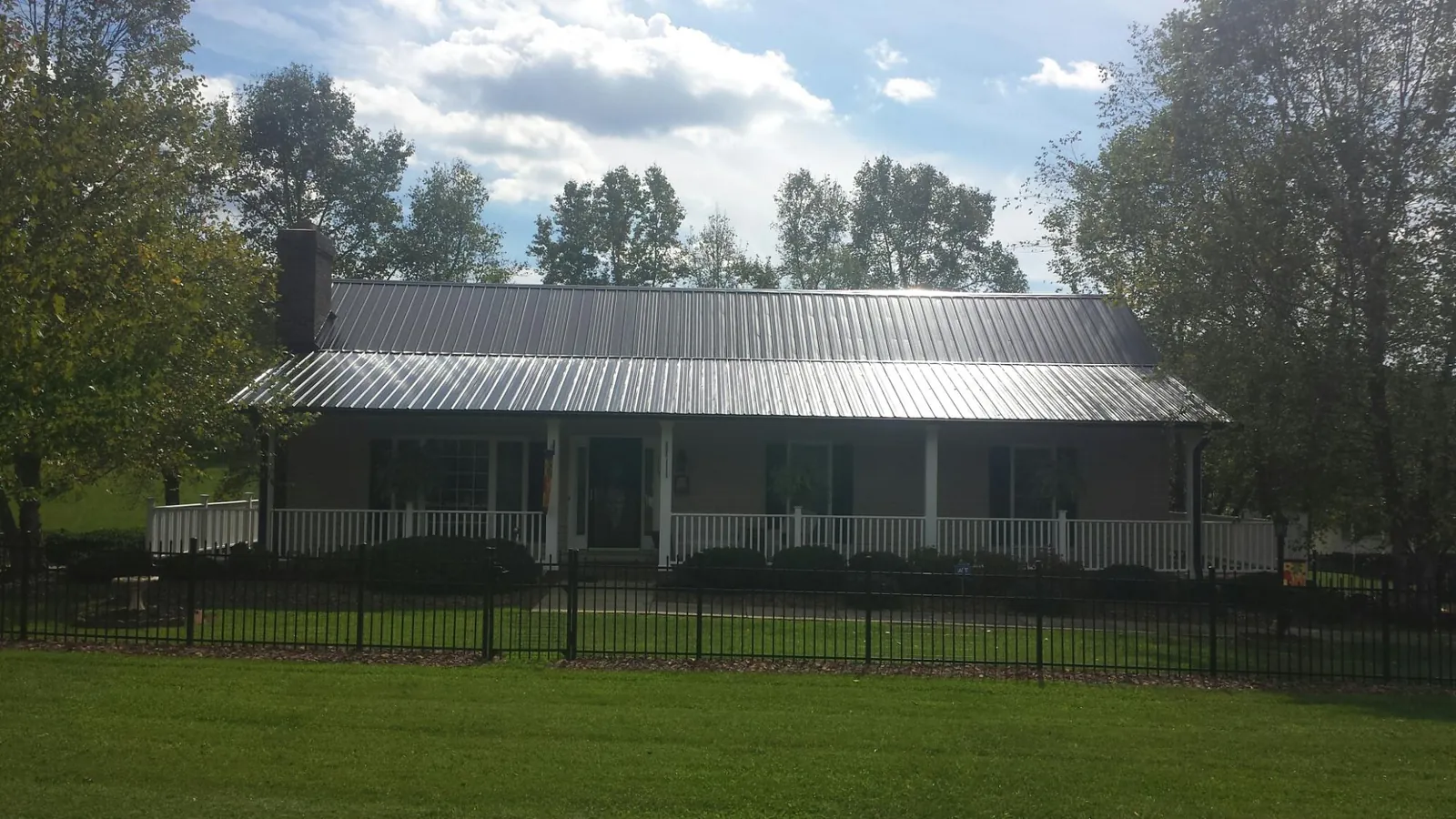 Gray metal roof on a brick ranch with a full width front porch — Gutter Guard Installation work by our crew in Bradley