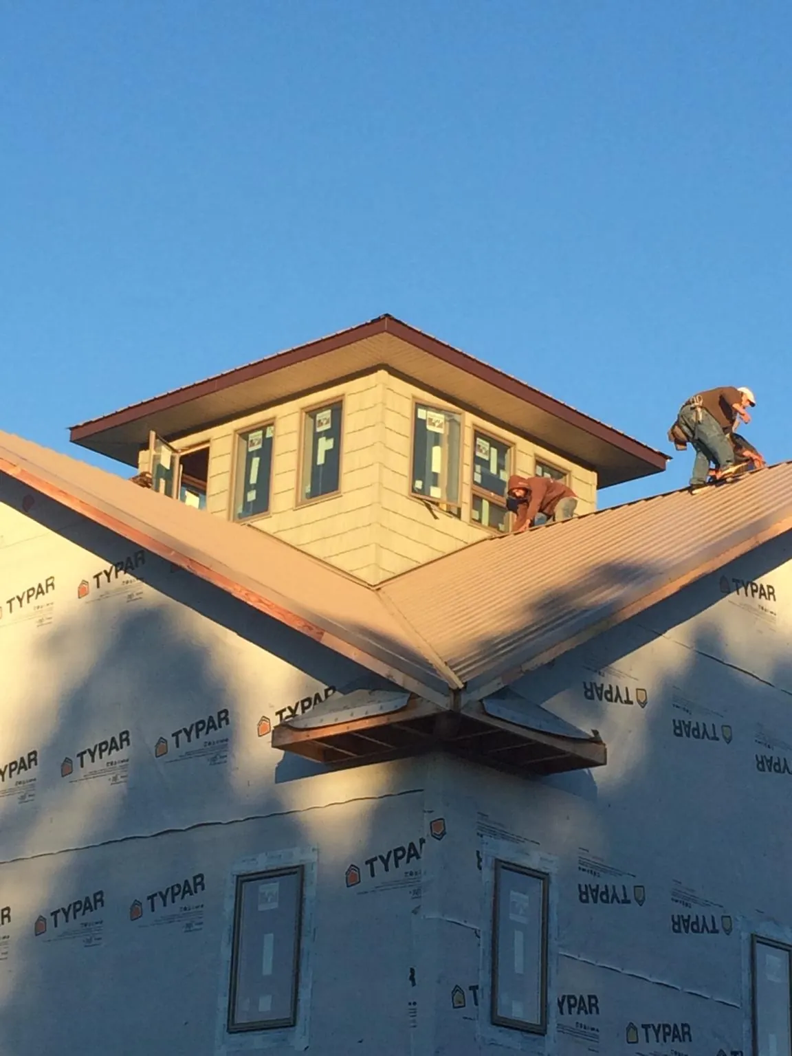 Roofers working around a rooftop cupola on a new metal roof at sunset — Roof Waterproofing in Bradley by Roofing Brothers
